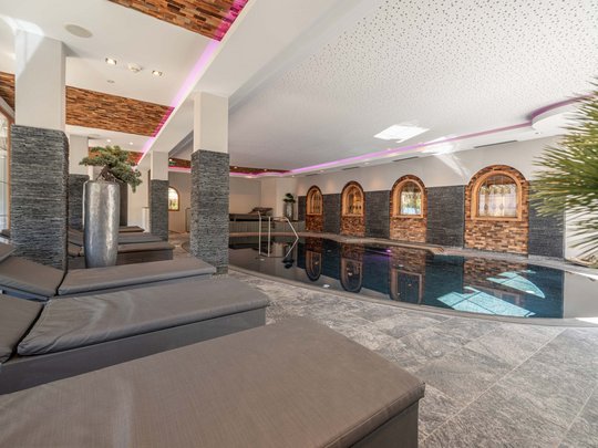 Saunadörfl und Bergsee in Ihrem Hotel in Tirol mit Pool Moderner Innenpool mit Liegestühlen und Dekor in Holztönen