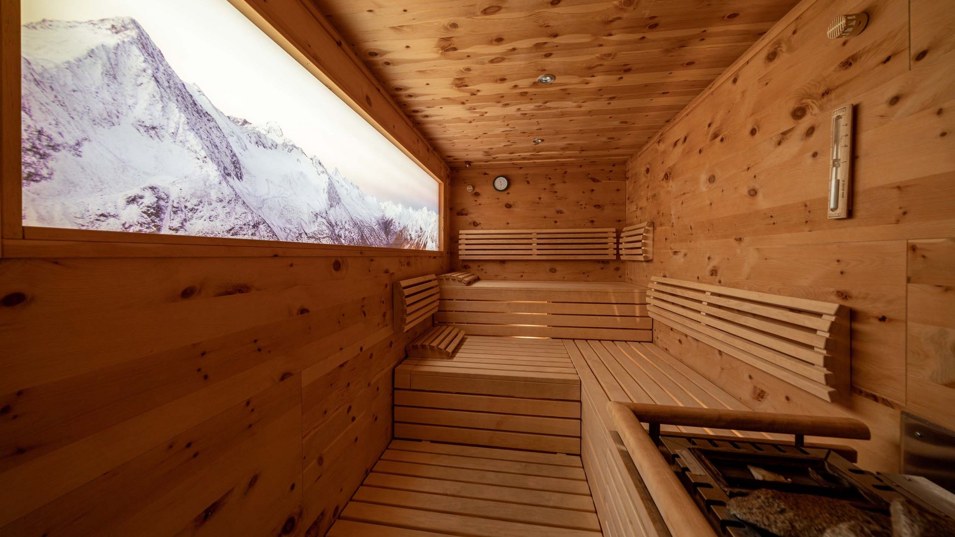 Saunadörfl und Bergsee in Ihrem Hotel in Tirol mit Pool Holzsauna mit Blick auf schneebedeckte Berge durch ein großes Fenster