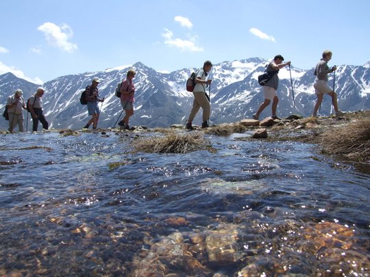 Wandern in den Ötztaler Alpen: von Ihrem Hotel in die Berge Gruppe von Wanderern mit Stöcken am Berg mit Schneegipfeln und klarem Wasser