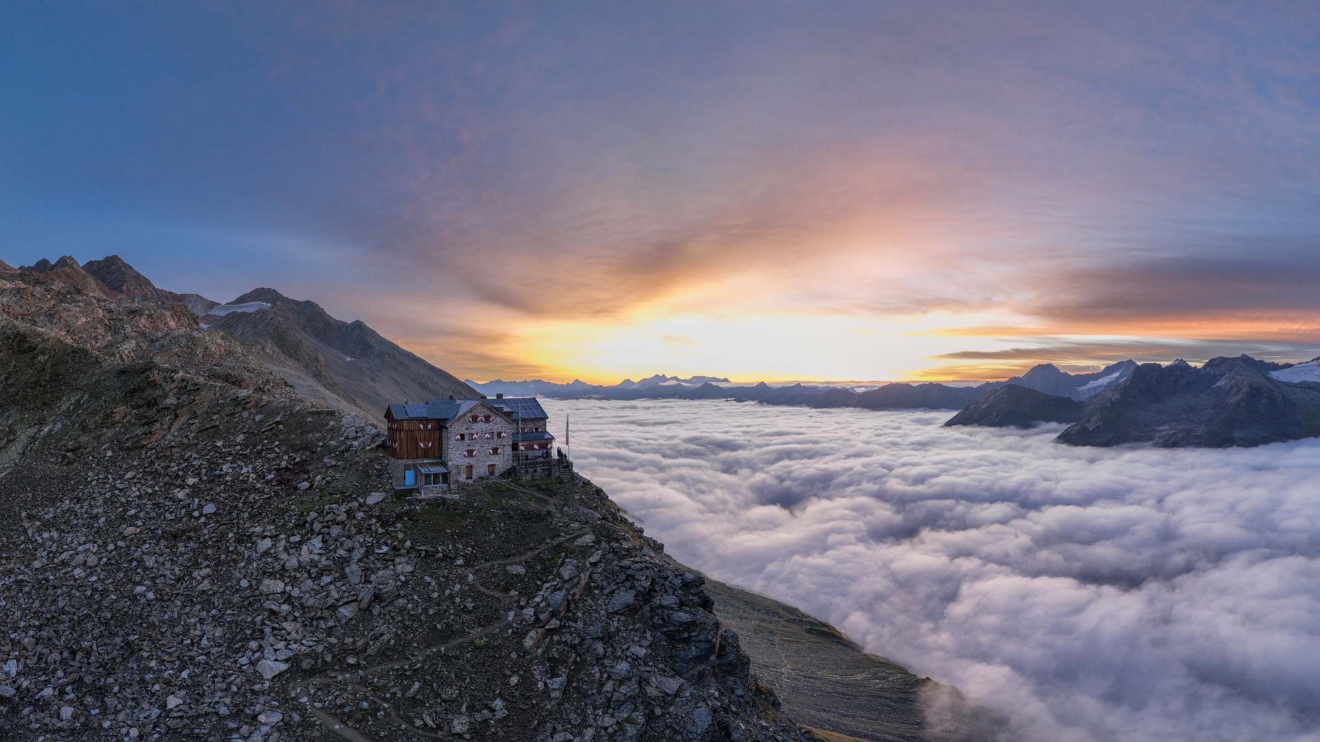 Our favourite tours – incl. the walk up to Similaun hut Mountain hut above clouds with sunset over rocky peaks