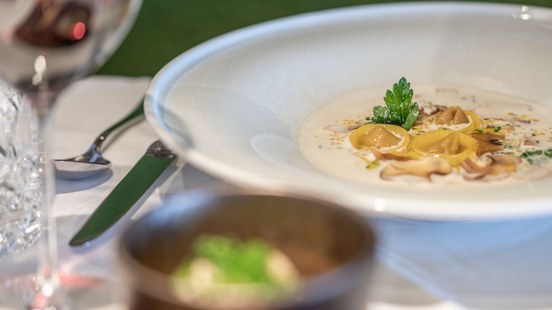 Natural indulgence at our restaurant in Vent Plate of tortellini in creamy mushroom sauce with glass of red wine on table