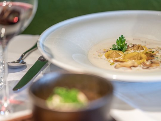 The heights of indulgence in Vent: our restaurant, Die Post Plate of tortellini in creamy mushroom sauce with glass of red wine on table
