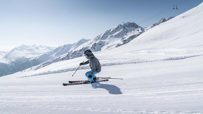 Skifahren? Aber ohne Massen! Skifahrer fährt auf frisch präparierter Piste in den schneebedeckten Alpen