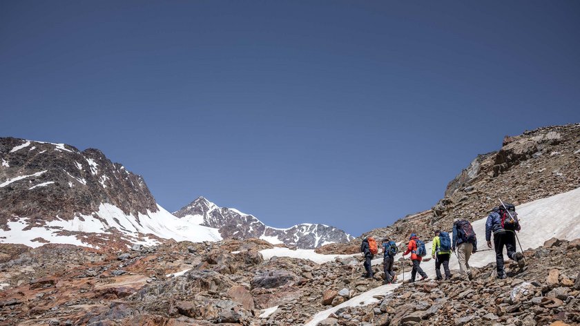 Ruhe und Natur: Orte der Stille nahe Vent Gruppe von Wanderern steigt auf felsigem Gelände in den verschneiten Bergen auf
