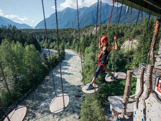 Natur- und Alpinhotel Post: Sehenswürdigkeiten im Ötztal Frau klettert gesichert über schwebende Podeste in Kletterpark über Fluss