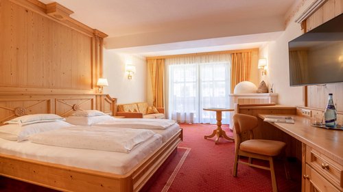 Your holiday in Vent: Enquire now with no obligation! Bright hotel room with two beds, sofa, desk, and balcony