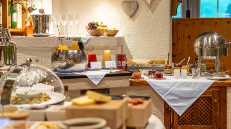Pictures of our mountain hotel in Vent Breakfast buffet with juices, fruits, bread, and spreads in cozy room
