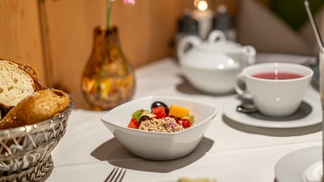 Pictures of our mountain hotel in Vent Breakfast table with muesli, fruit, bread, and tea in white dishes