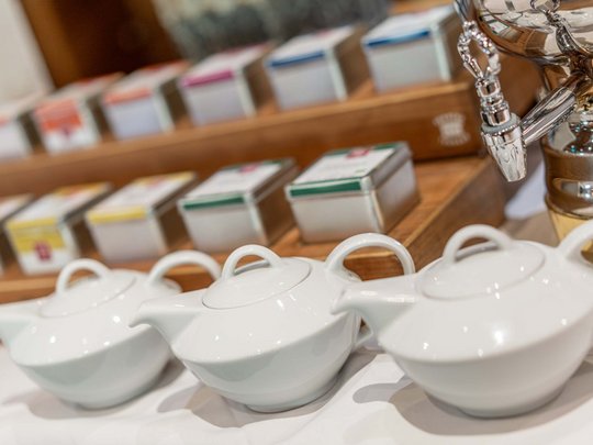 Morning indulgence in Vent: our accommodation with breakfast White teapots in front of tea tins and a samovar