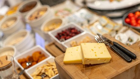 Pictures of our mountain hotel in Vent Two slices of cheese on wooden board with ingredients and kitchen utensils in background