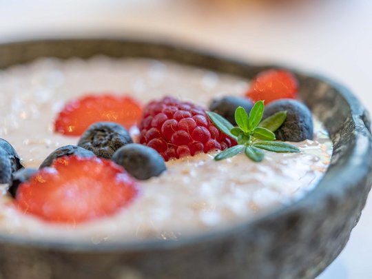 Morning indulgence in Vent: our accommodation with breakfast Porridge with fresh berries in a gray bowl
