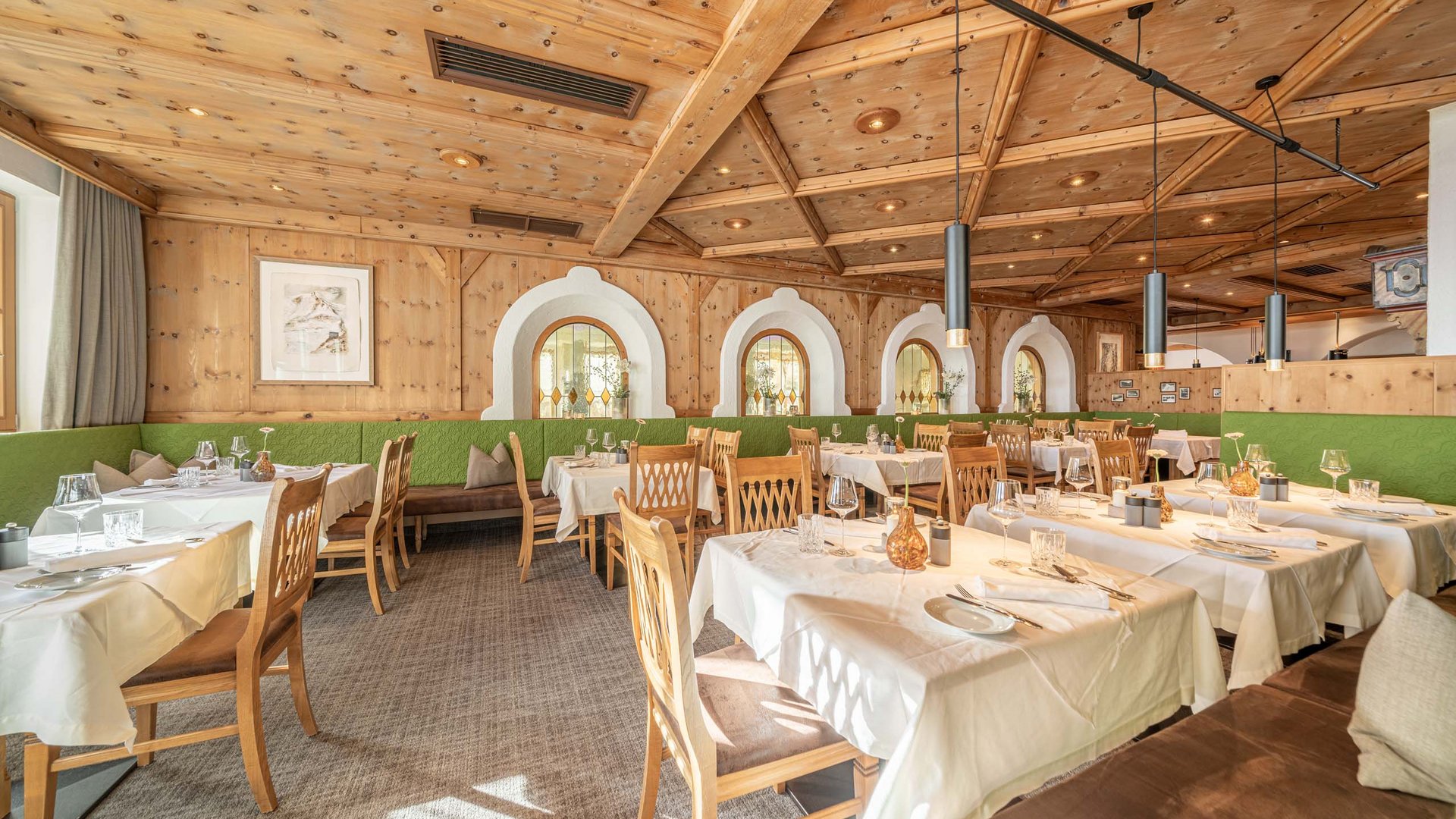 The heights of indulgence in Vent: our restaurant, Die Post Bright restaurant with wooden walls, green bench seating, and set tables