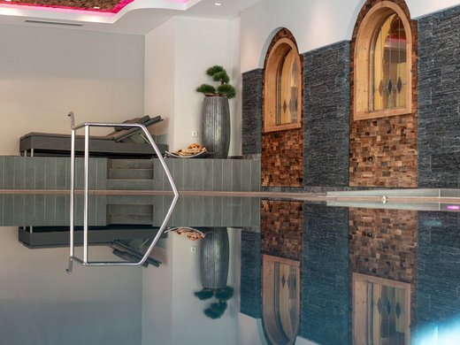 Lieu de rêve Vent : notre hôtel dans l’Ötztal Piscine intérieure avec chaises longues et murs avec fenêtres décoratives en bois