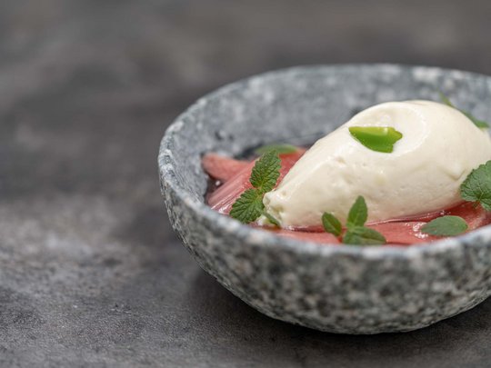 The heights of indulgence in Vent: our restaurant, Die Post Creamy dessert with green garnish on red fruit in a gray bowl