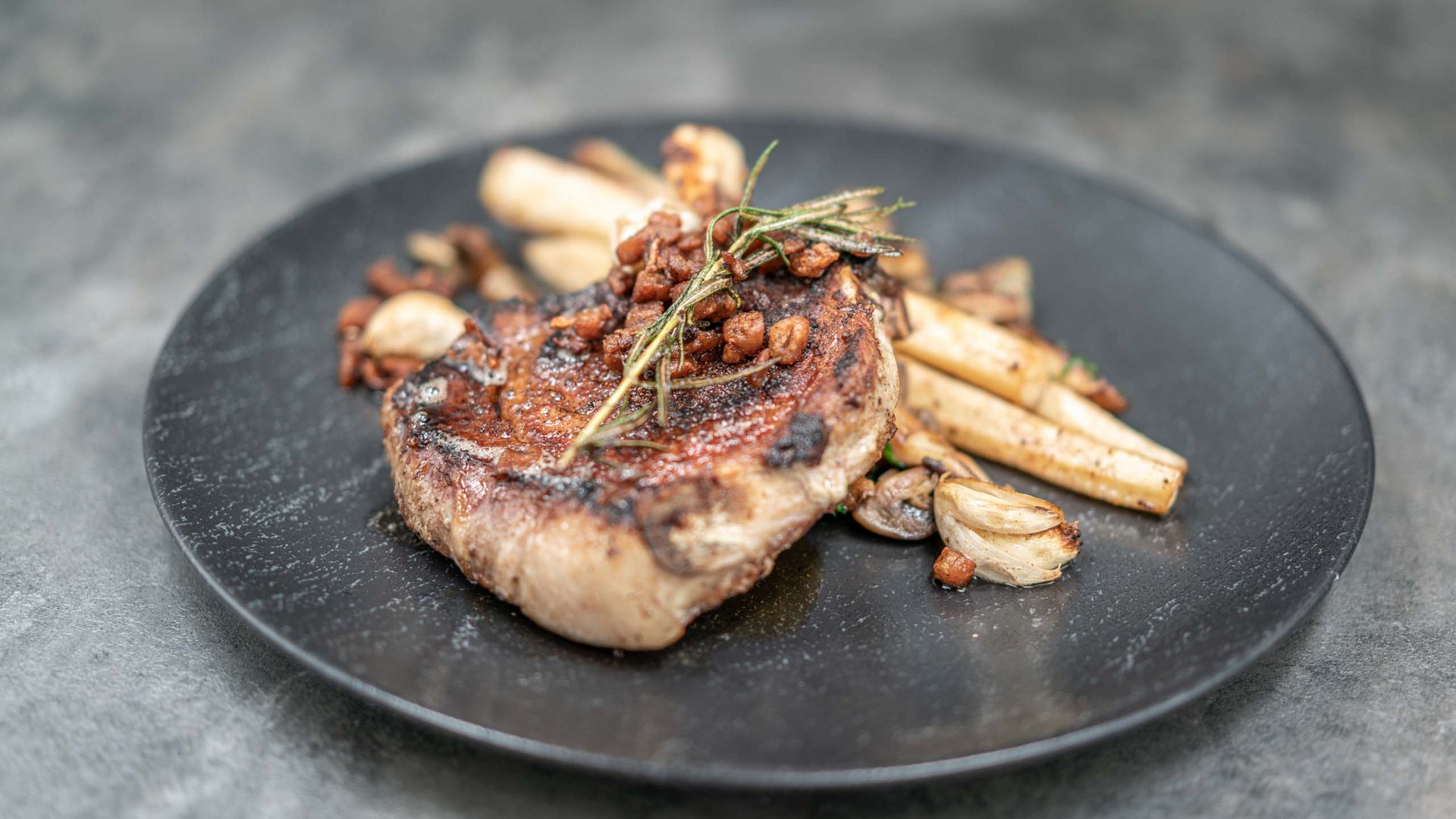 The heights of indulgence in Vent: our restaurant, Die Post Grilled steak with rosemary and vegetables on a black plate