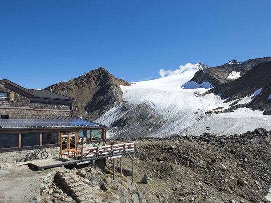 Alpinclub Similaun: durch die Liebe zum Berg vereint Berghütte neben Gletscher und Felsen unter klarem blauem Himmel