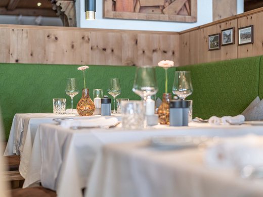 L’hôtel de bien-être dans l’Ötztal : du calme bienfaisant Tables dressées avec nappes blanches et banquettes vertes dans un restaurant