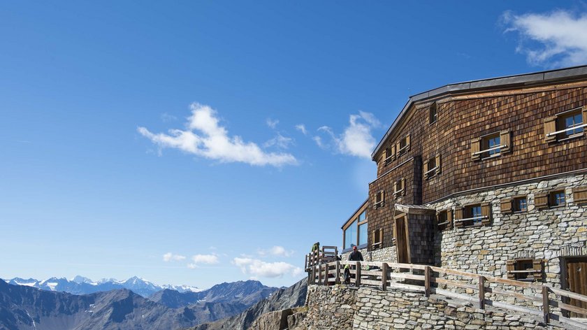 Une aventure alpine dans l’Ötztal Refuge en bois et pierre avec vue sur les montagnes alpines sous un ciel bleu