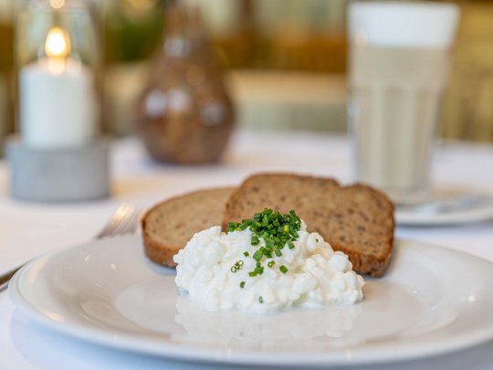 Morning indulgence in Vent: our accommodation with breakfast Cottage cheese with chives and whole grain bread on white plate