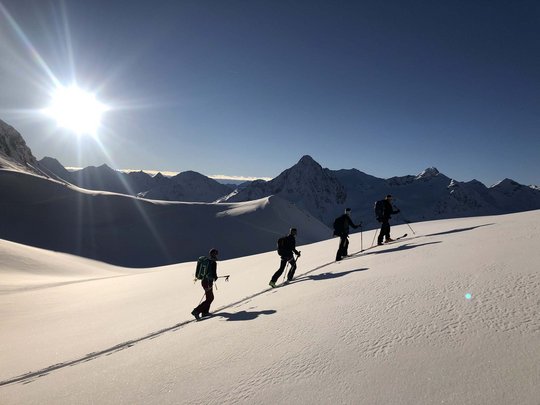 Von Ihrem Hotel zum Schneeschuh- und Winterwandern in Vent Vier Skitourengeher steigen bei Sonnenschein einen schneebedeckten Berg hinauf