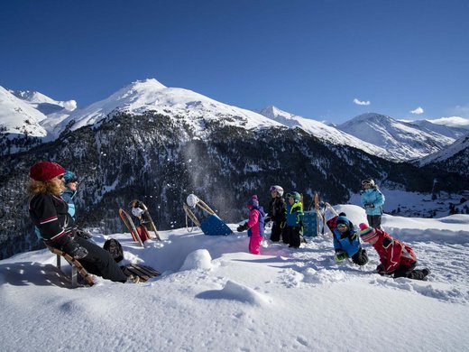 Winterwandern, Langlaufen und Rodeln in Vent Kinder und Erwachsene mit Schlitten in verschneiter Berglandschaft bei Sonnenschein