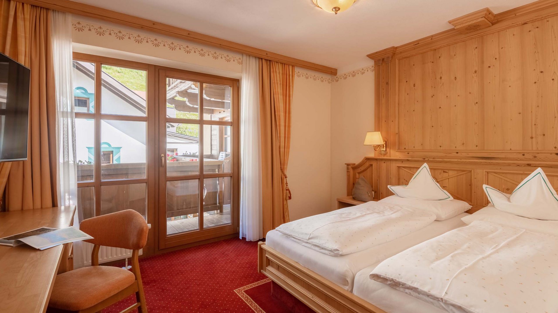 L’hôtel de bien-être dans l’Ötztal : du calme bienfaisant Chambre double confortable avec mobilier en bois et balcon aux couleurs chaudes