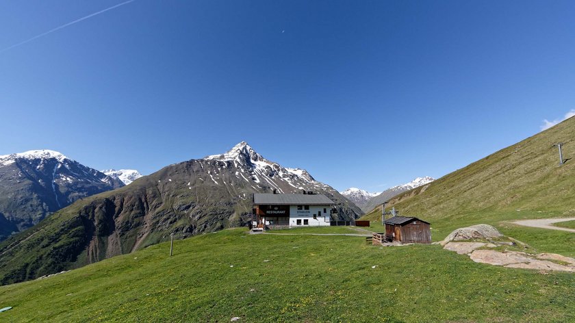 Wandern und alpine Küche im Ötztal Bergrestaurant auf grüner Alp mit schneebedeckten Bergen und klarem Himmel