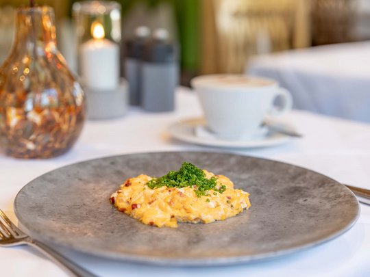 Morning indulgence in Vent: our accommodation with breakfast Scrambled eggs with chives on a gray plate in a restaurant setting