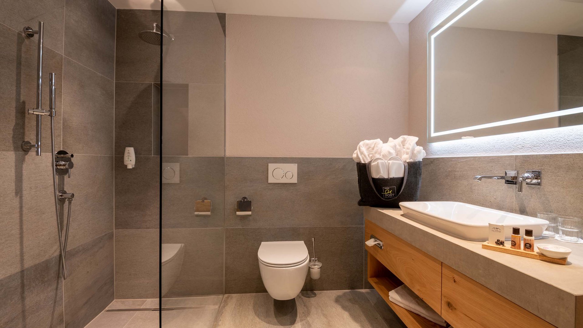 L’hôtel de bien-être dans l’Ötztal : du calme bienfaisant Salle de bains moderne avec douche, WC et meuble lavabo en bois avec miroir éclairé