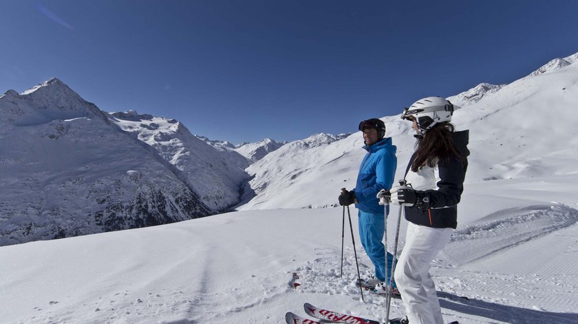 Ein rundum gelungener Winterurlaub Zwei Skifahrer stehen auf schneebedecktem Berg mit Bergpanorama im Hintergrund