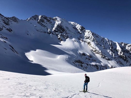 Backcountry skiing near Vent: start directly from our hotel Skier on snow in front of snow-covered mountains under clear sky