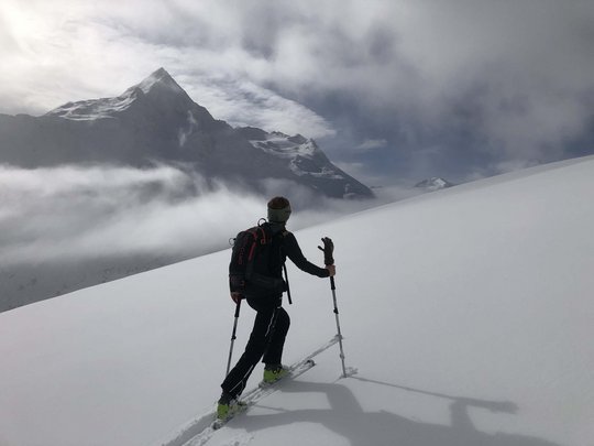 Backcountry skiing near Vent: start directly from our hotel Person ski touring on snow-covered mountain with fog and mountain peaks