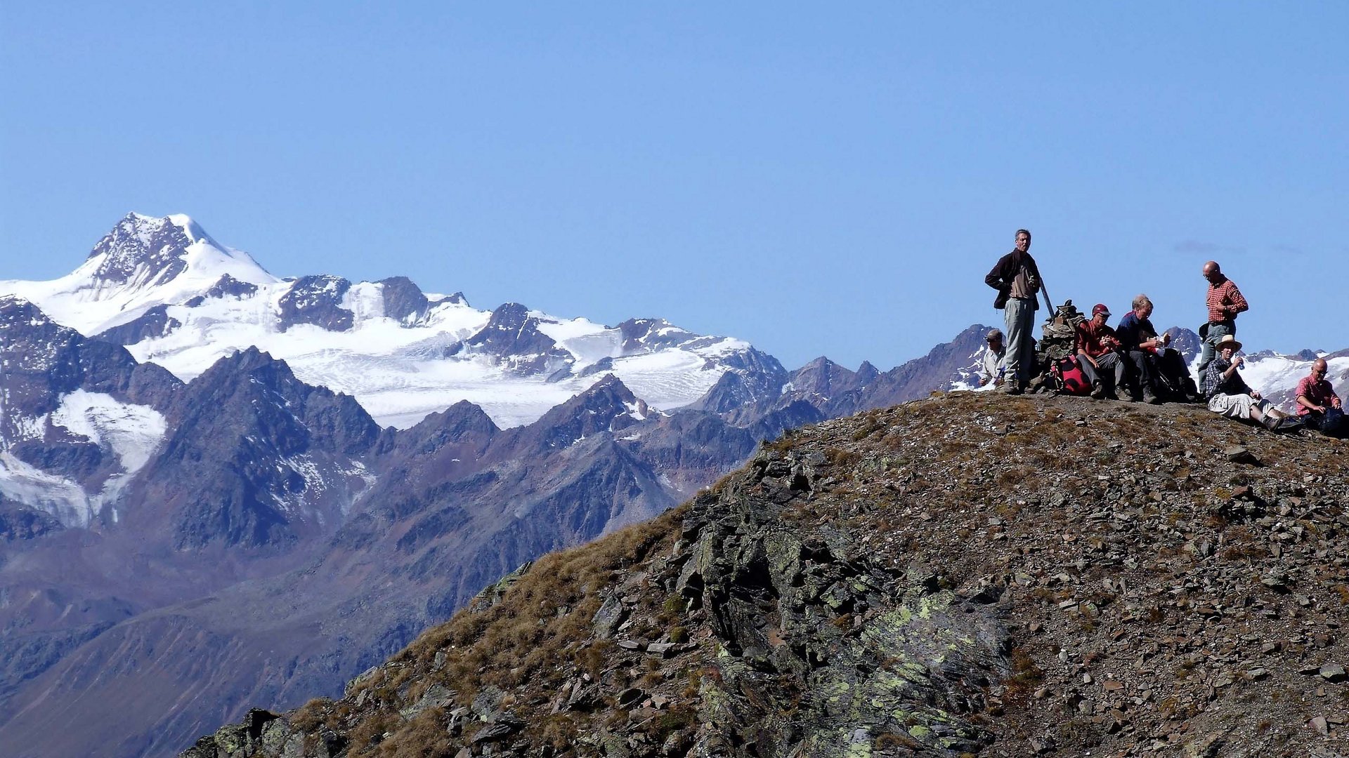 Wandern in den Ötztaler Alpen: von Ihrem Hotel in die Berge Gruppe von Wanderern auf einem Berggipfel vor schneebedeckten Alpen