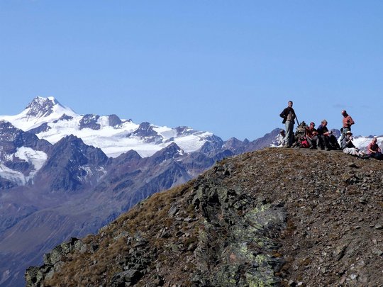 Wandern in den Ötztaler Alpen: von Ihrem Hotel in die Berge Gruppe von Wanderern auf einem Berggipfel vor schneebedeckten Alpen