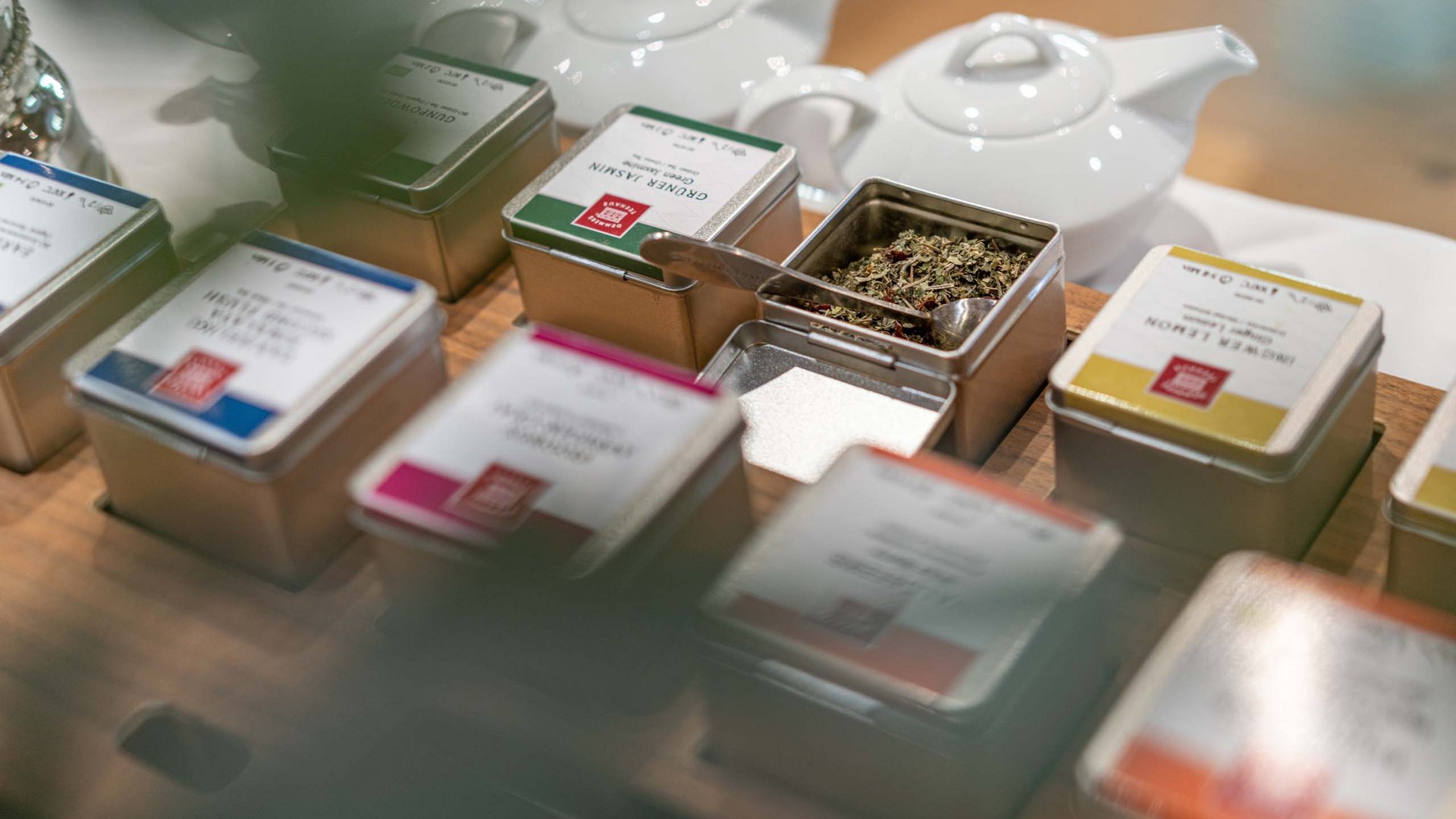 Morning indulgence in Vent: our accommodation with breakfast Assorted tea tins with loose tea and white teapots on wooden table