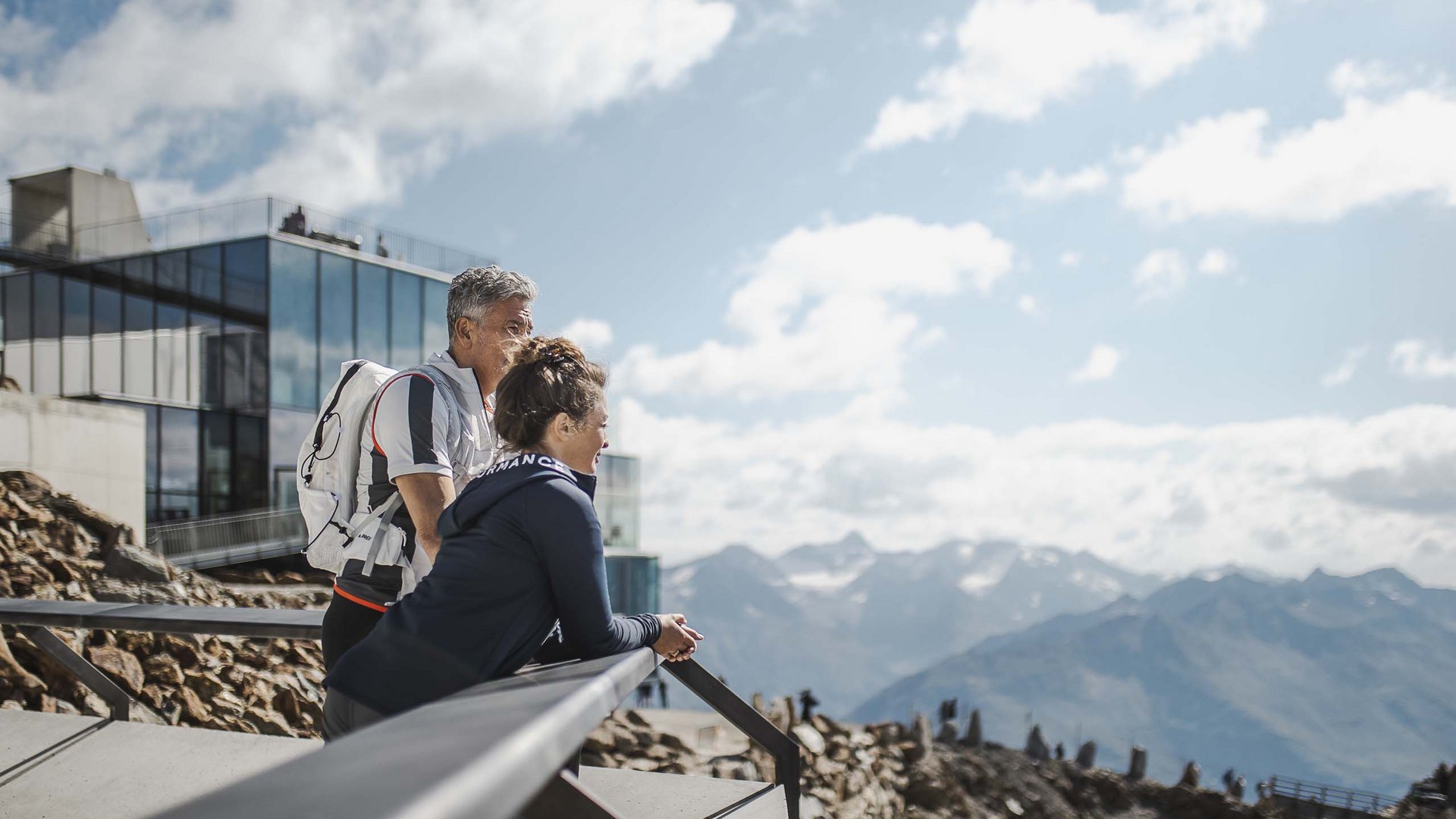 Ötztal Summer Card : découvrir l’Ötztal depuis votre hôtel Deux randonneurs regardent un paysage montagneux depuis une terrasse moderne