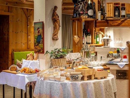 Morgendlicher Genuss in Vent: Ihre Unterkunft mit Frühstück Buffet mit Brot, Käse, Getränken und Frühstückszutaten in rustikalem Raum