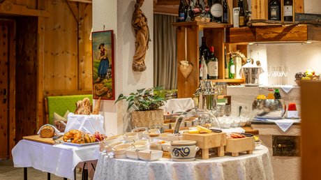 Pictures of our mountain hotel in Vent Buffet with bread, cheese, drinks, and breakfast items in a rustic setting