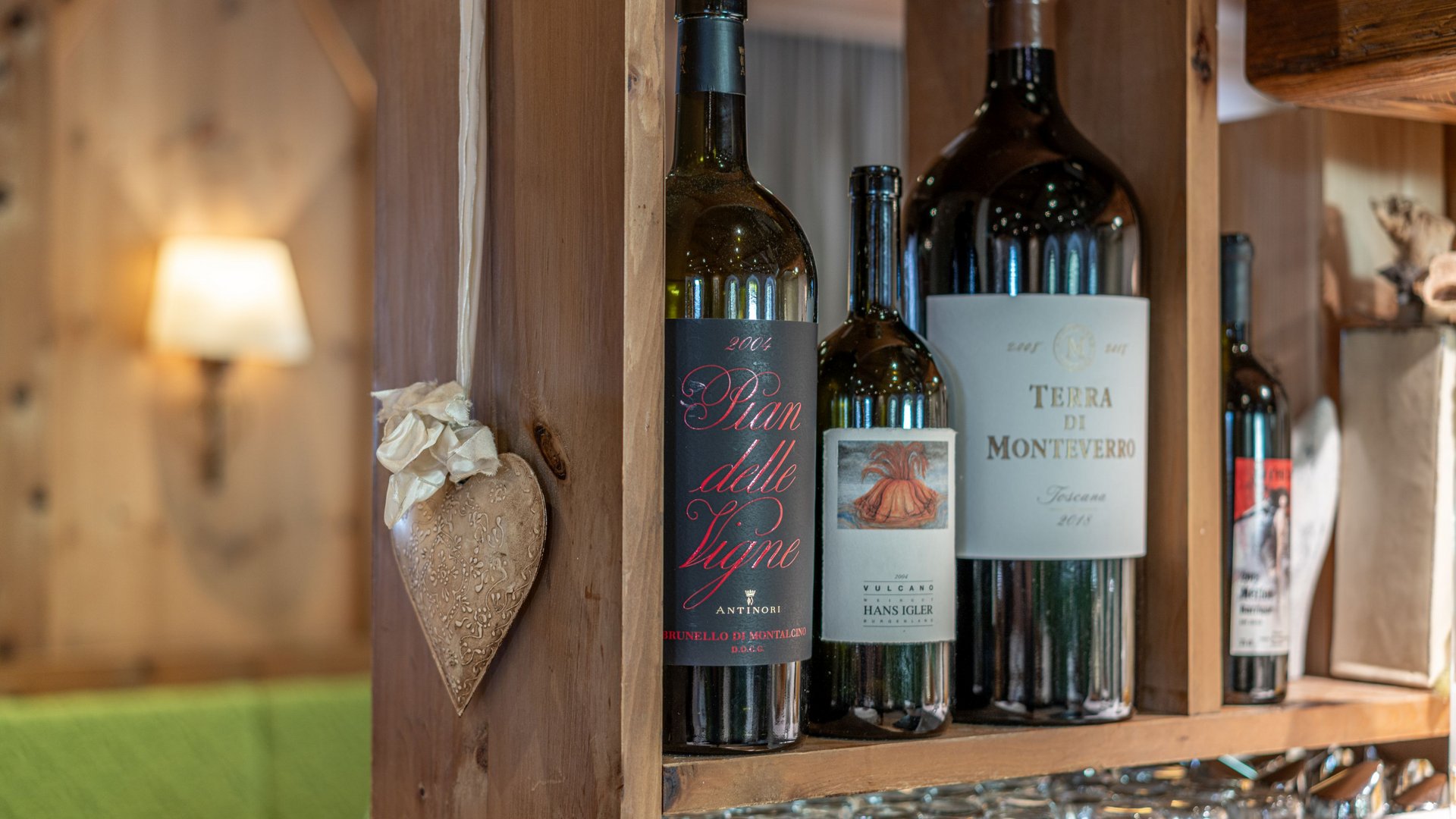 Natural indulgence at our restaurant in Vent Various wine bottles on a rustic wooden shelf with glasses underneath