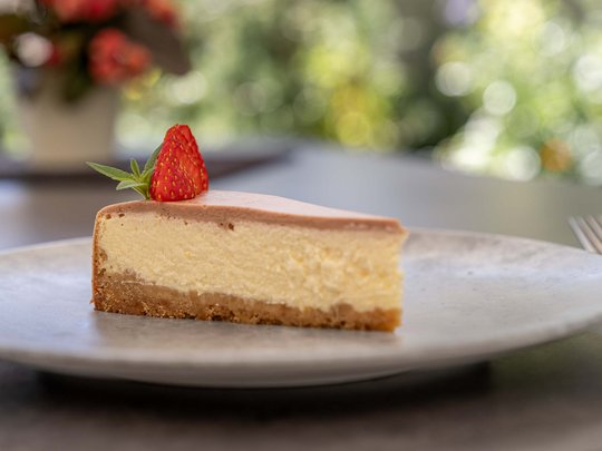 Morning indulgence in Vent: our accommodation with breakfast A slice of cheesecake with strawberry on a white plate