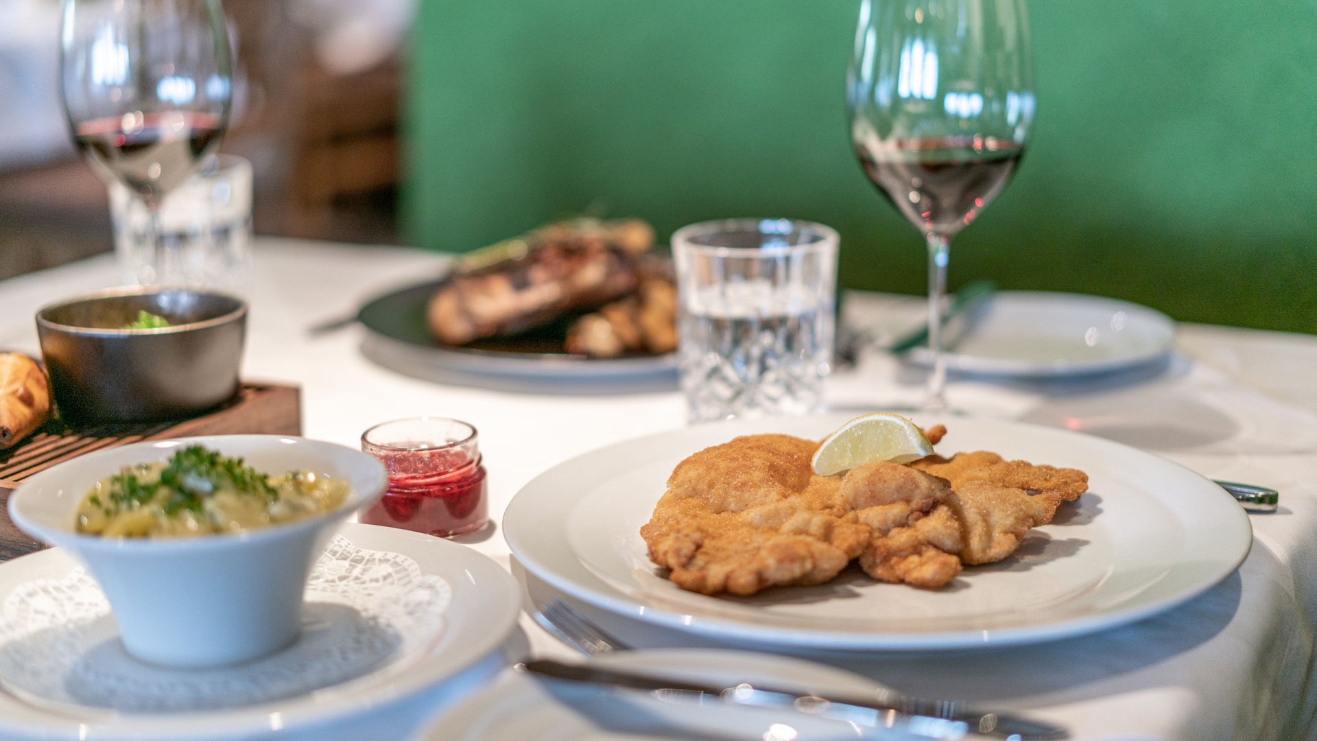 Natural indulgence at our restaurant in Vent Table with Wiener schnitzel, lingonberry sauce, potato salad and red wine in restaurant