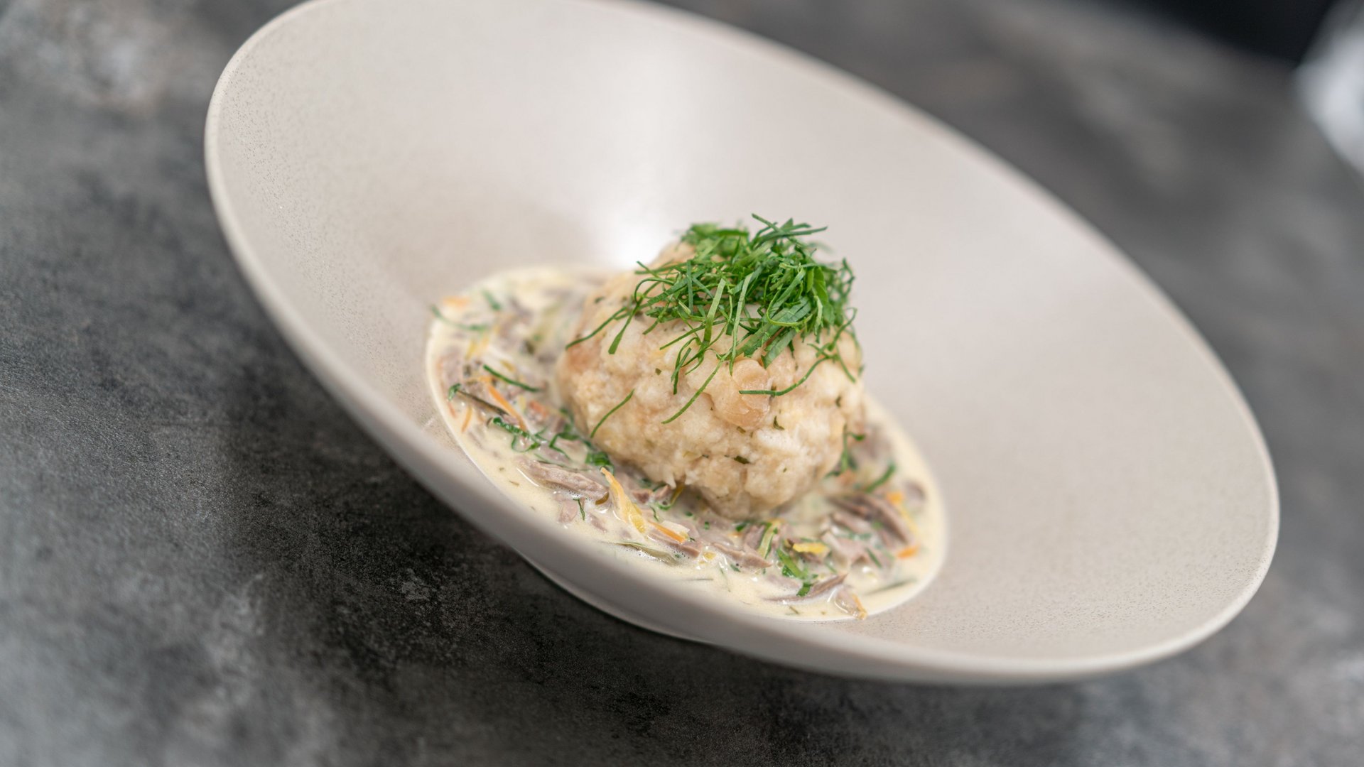 The heights of indulgence in Vent: our restaurant, Die Post Dumpling with cream sauce and fresh herbs on a white plate