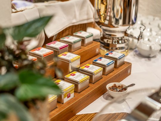 Morgendlicher Genuss in Vent: Ihre Unterkunft mit Frühstück Teedosen in einem Holzständer und ein silberner Tee- oder Wasserkessel auf einem Tisch