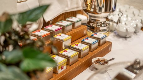 Pictures of our mountain hotel in Vent Tea tins in wooden holder and a silver tea or water kettle on a table